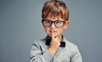 Pensive young boy with his index finger over his mouth